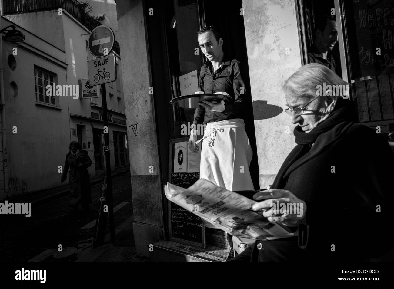 Mann liest Zeitung, als die Kellner seinen Kaffee bringt. Stockfoto