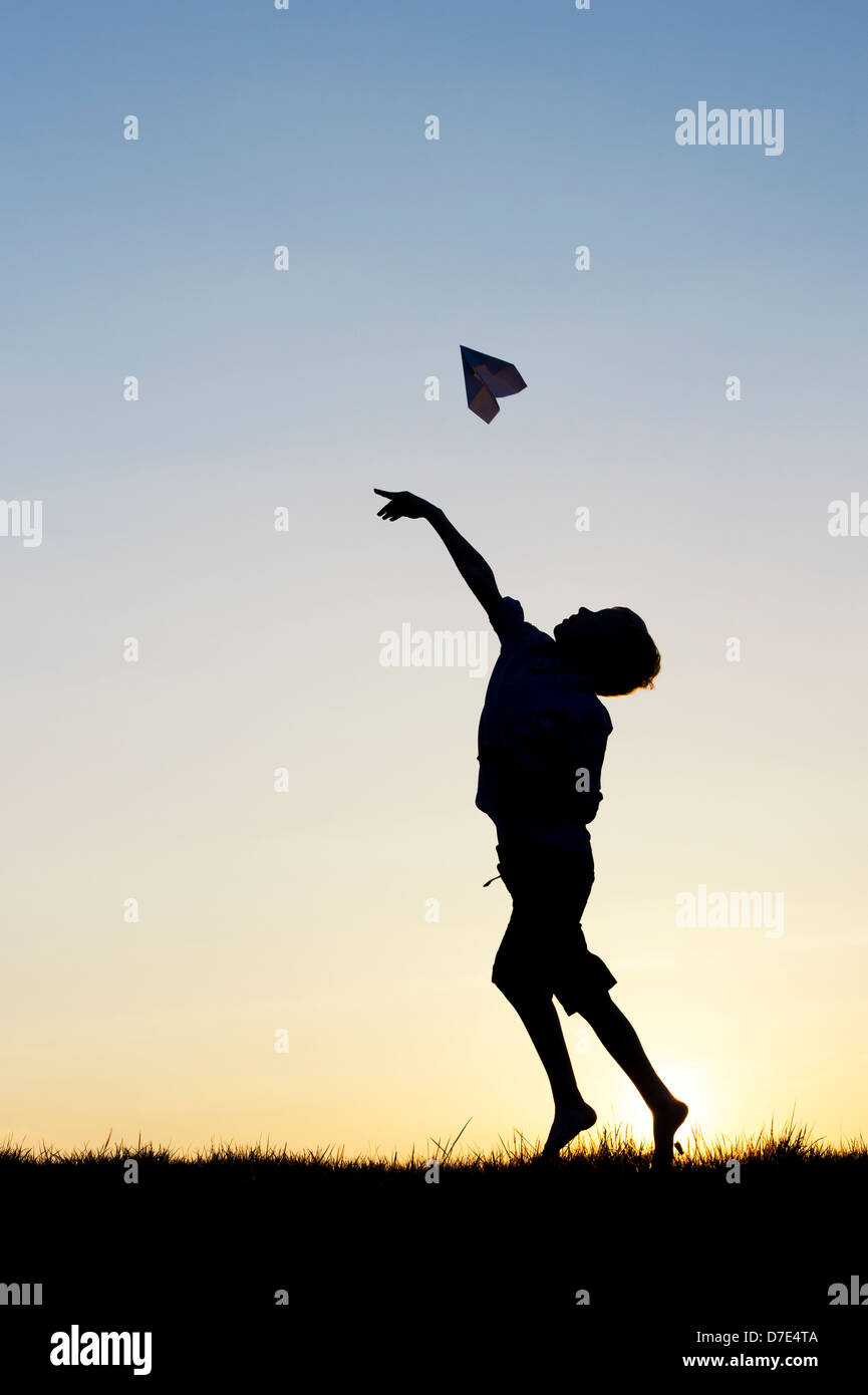 Junge werfen ein Papier Flugzeug bei Sonnenuntergang. Silhouette Stockfoto