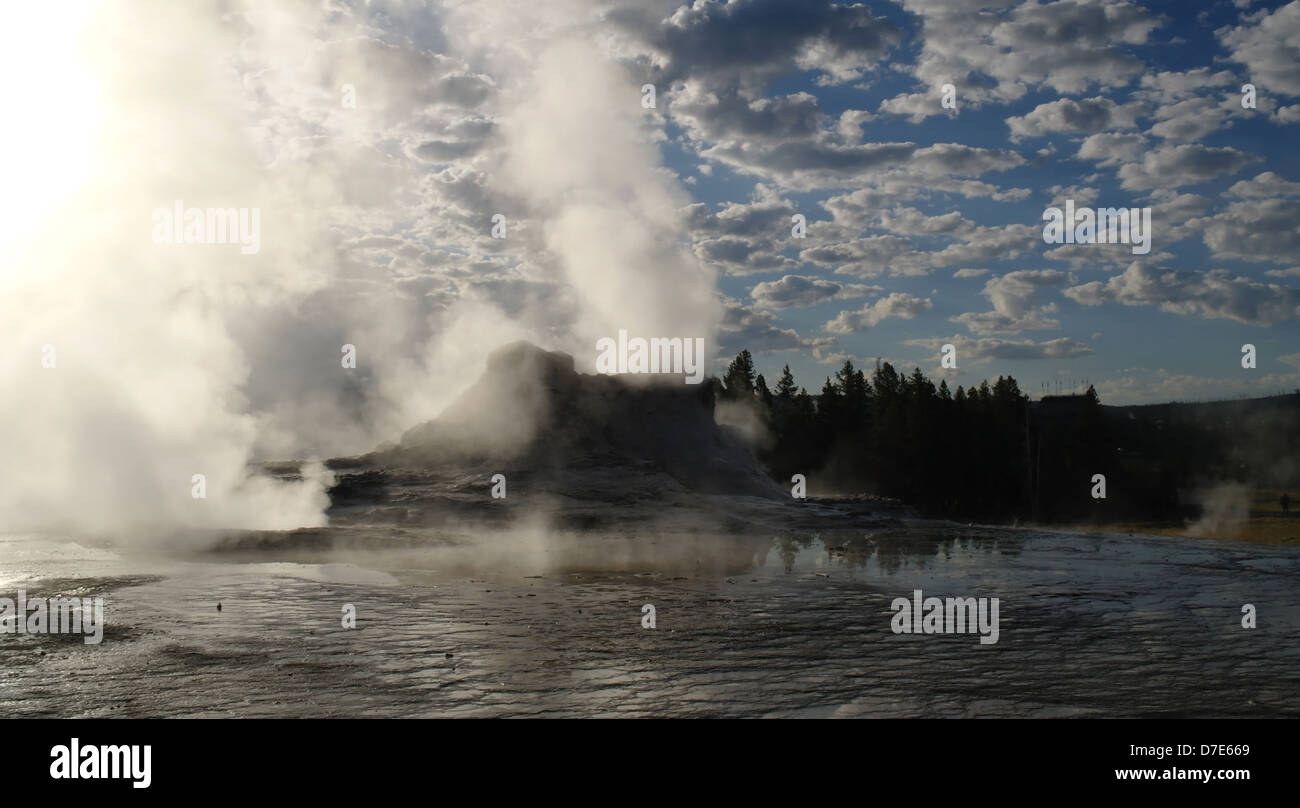 Am frühen Morgen blauer Himmel weiße Wolken anzeigen Dampf steigt aus dunklen grauen Sinter Kegel Castle Geyser, Upper Geyser Basin, Yellowstone Stockfoto