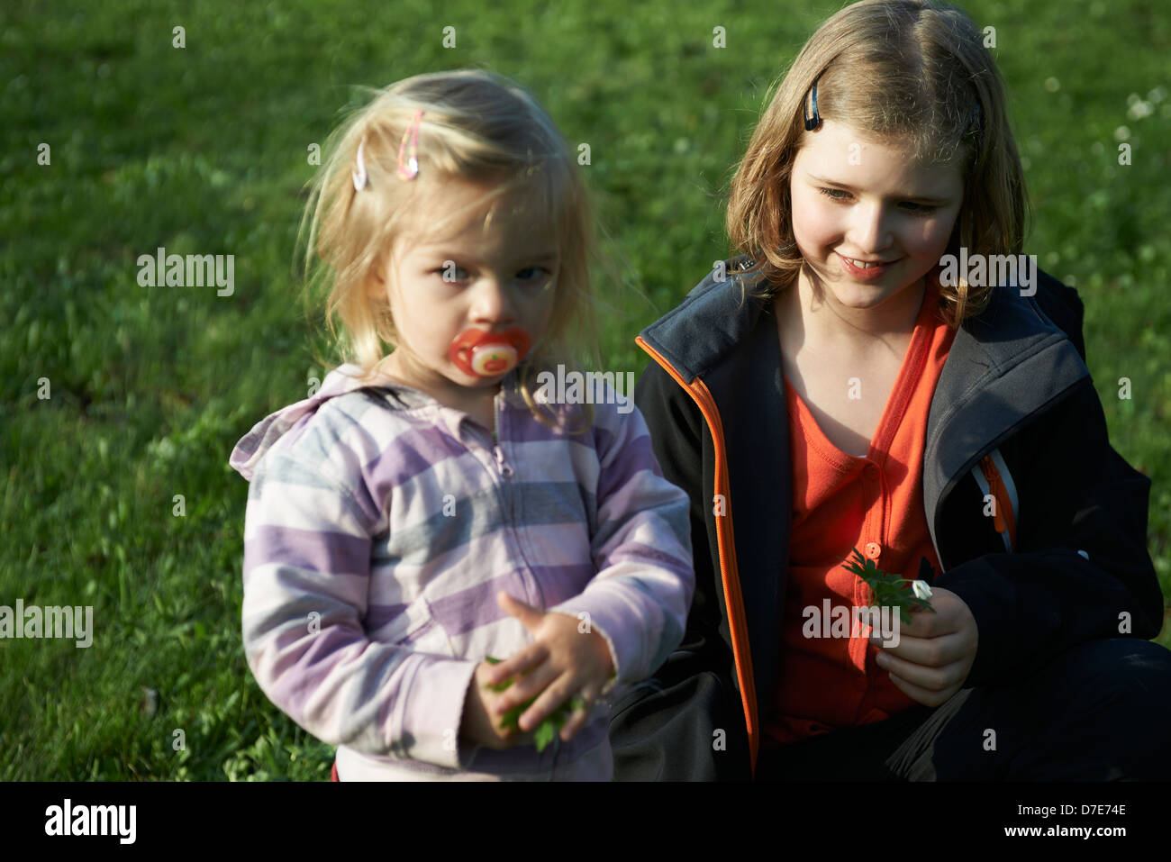 Zwei Kinder blond Mädchen spielen mit Rasen Garten und Blumen Sommerzeit Stockfoto