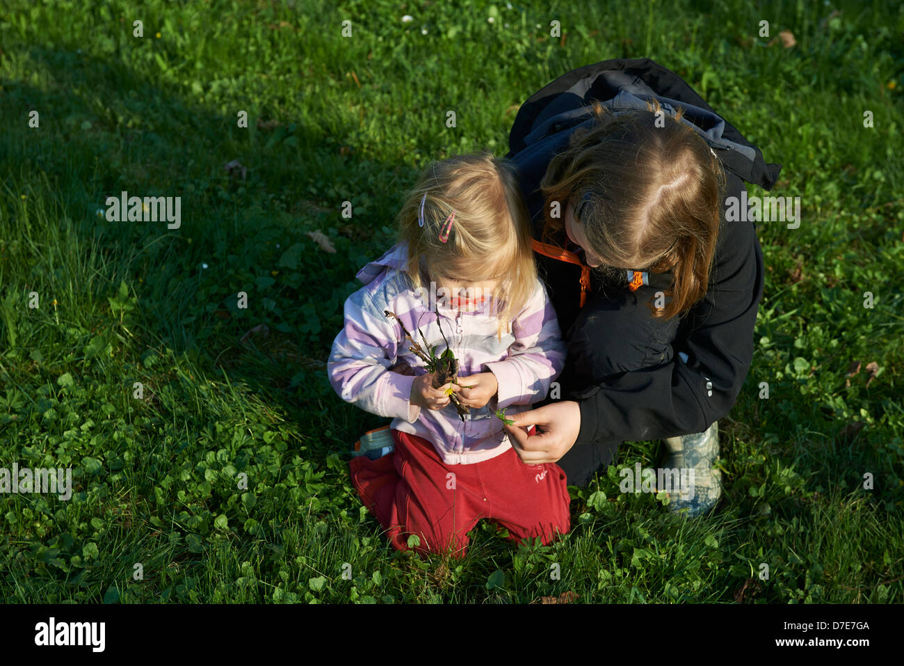 Zwei Kinder blond Mädchen spielen mit Rasen Garten und Blumen Sommerzeit Stockfoto