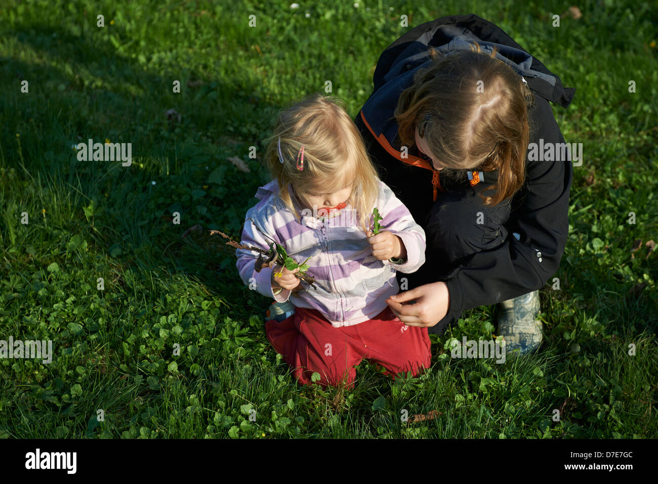 Zwei Kinder blond Mädchen spielen mit Rasen Garten und Blumen Sommerzeit Stockfoto