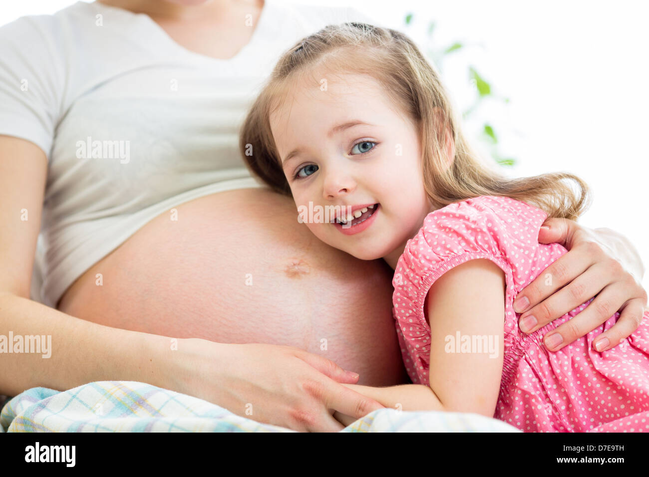 glückliches Kind Mädchen umarmt Bauch der schwangeren Mutter Stockfoto