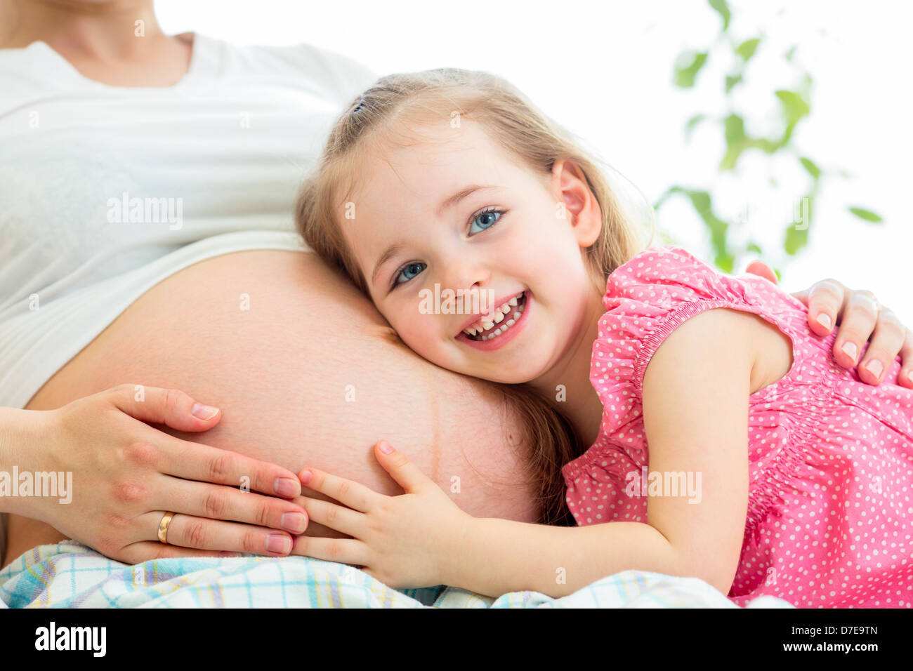 glückliches Kind Mädchen umarmt Bauch der schwangeren Mutter Stockfoto