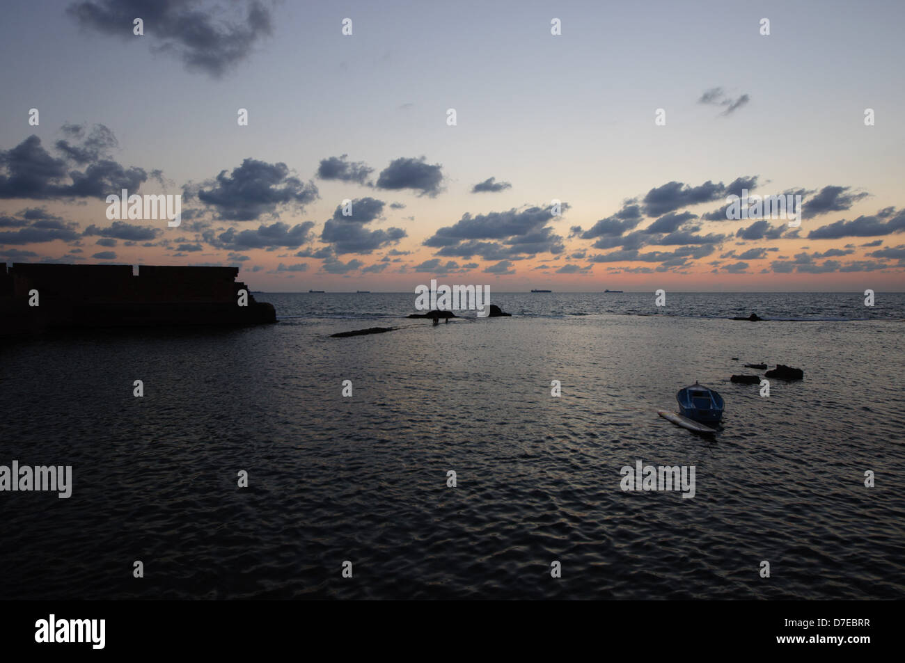 Weitwinkel-Blick auf das Meer und ein Teil der alten Stadtmauer in Akko, Israel. Einbruch der Dunkelheit. Darunter ein Fischerboot Stockfoto