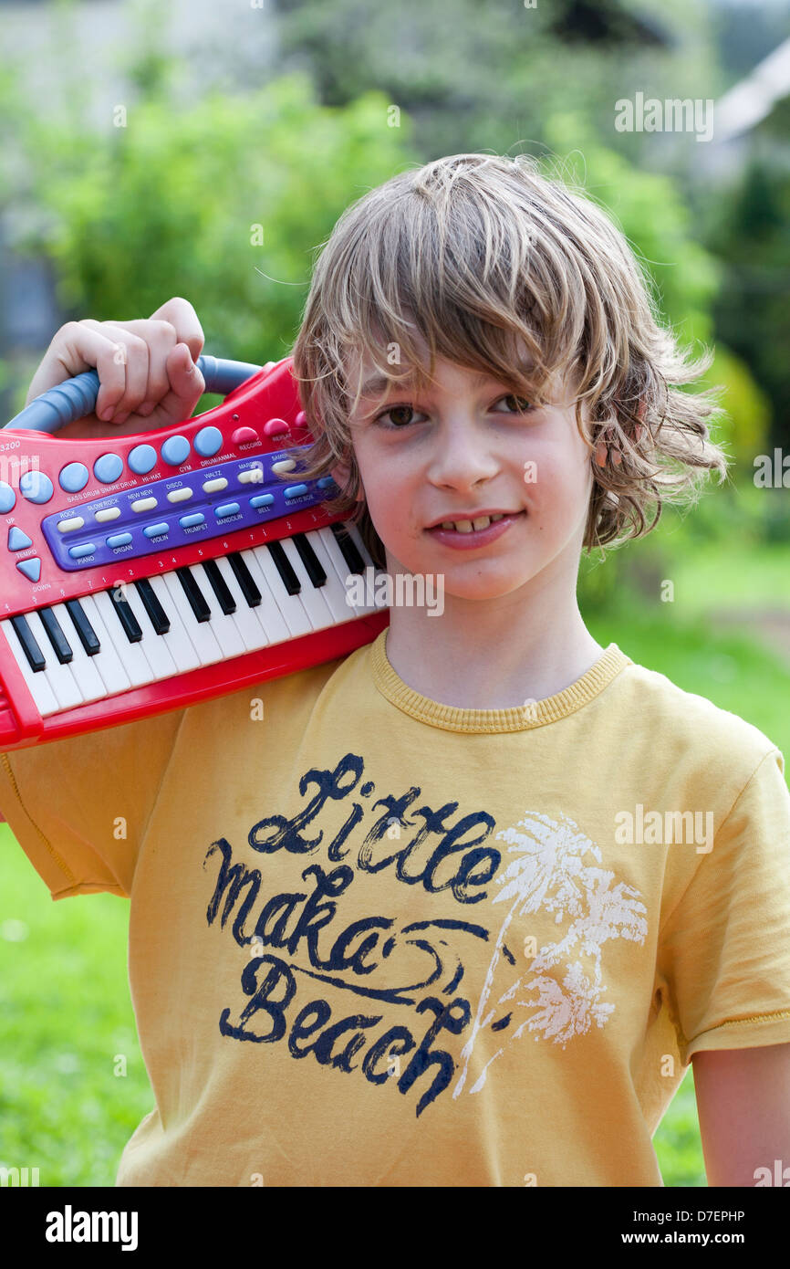 Bildnis eines Knaben mit Tastatur spielen im Freien im Garten. Stockfoto