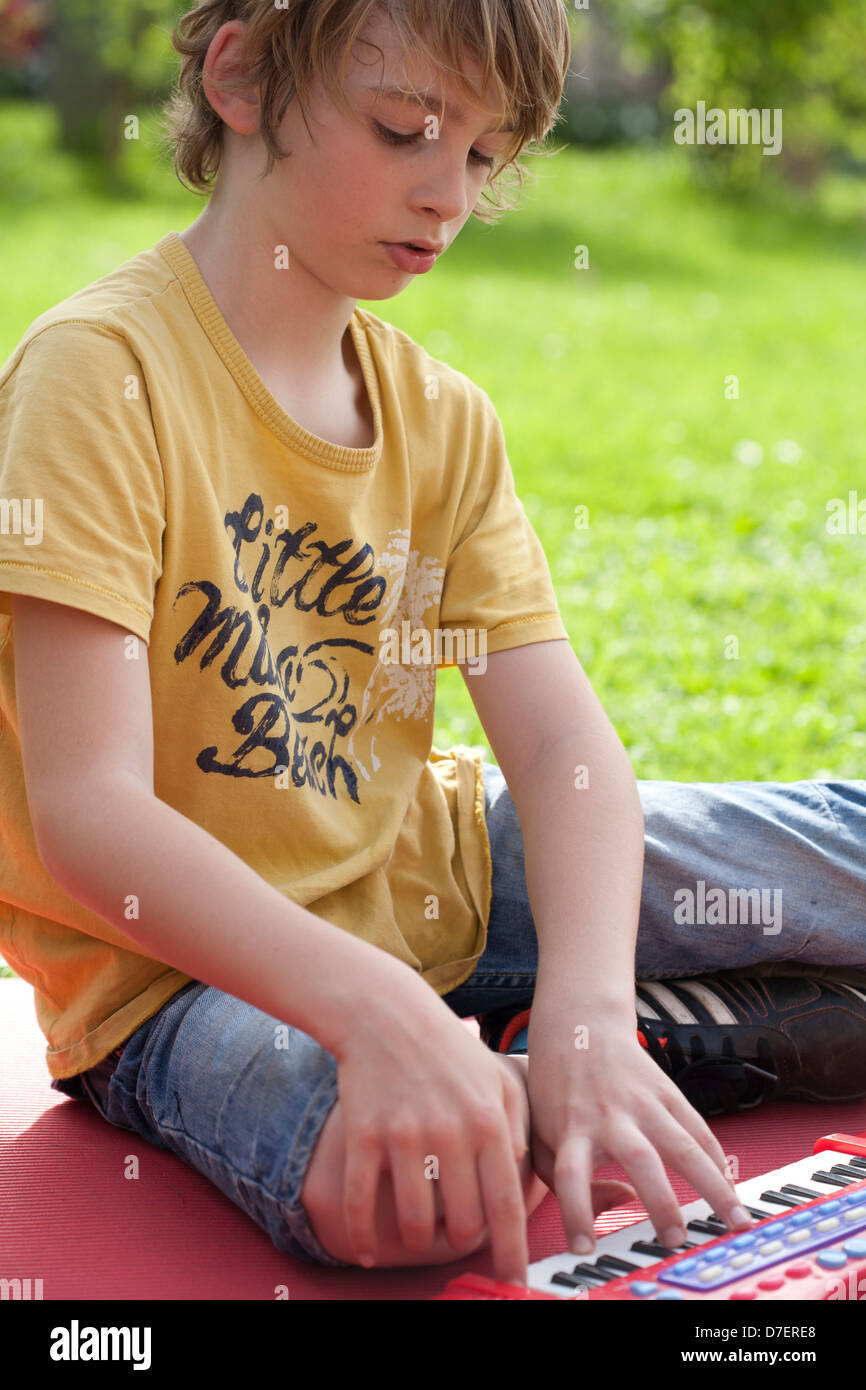 Bildnis eines Knaben mit Tastatur spielen im Freien im Garten. Stockfoto