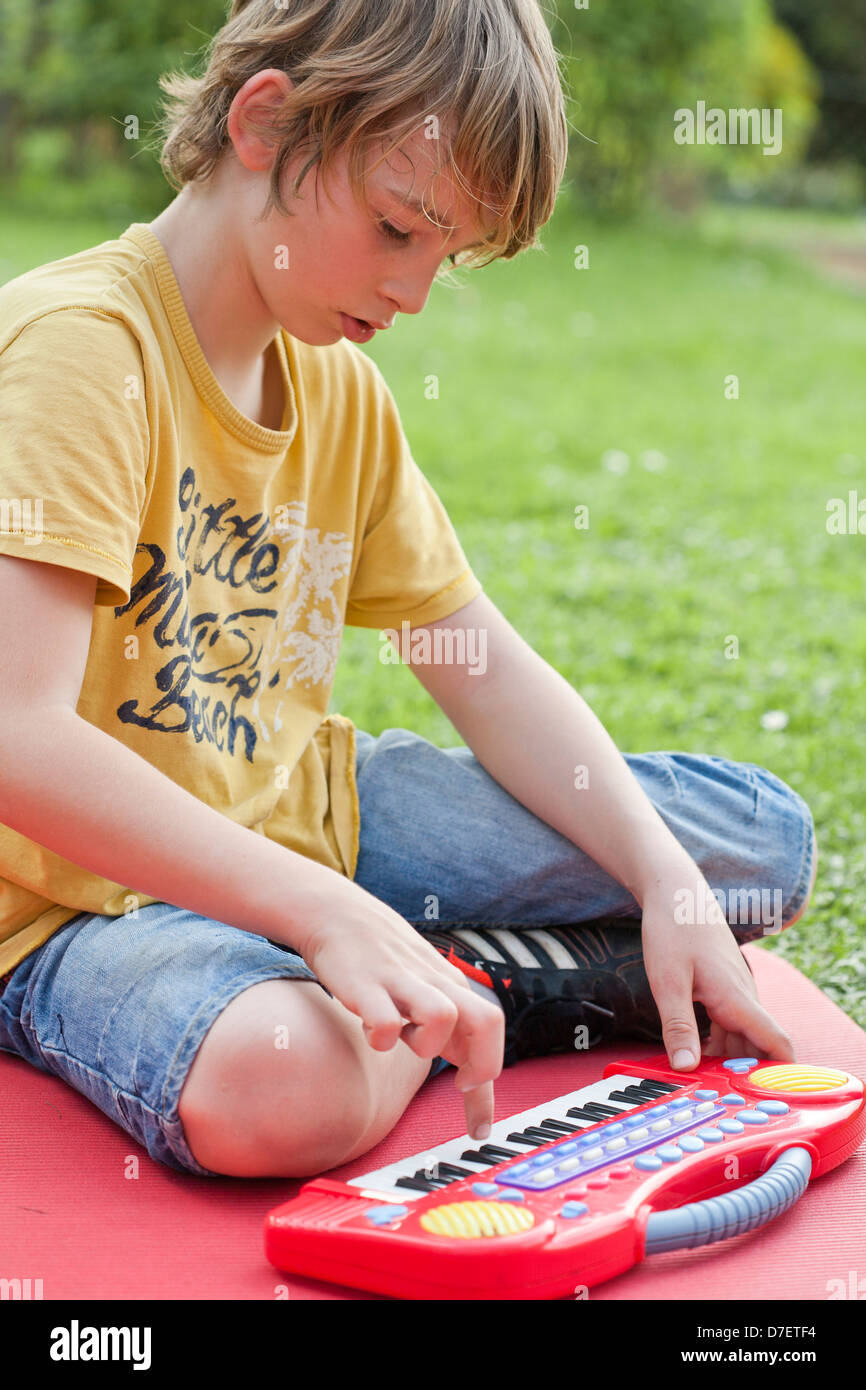 Bildnis eines Knaben mit Tastatur spielen im Freien im Garten. Stockfoto