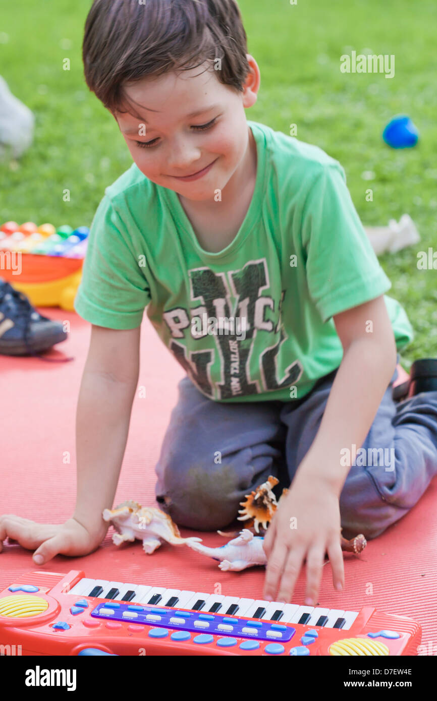 Bildnis eines Knaben mit Tastatur spielen im Freien im Garten. Stockfoto