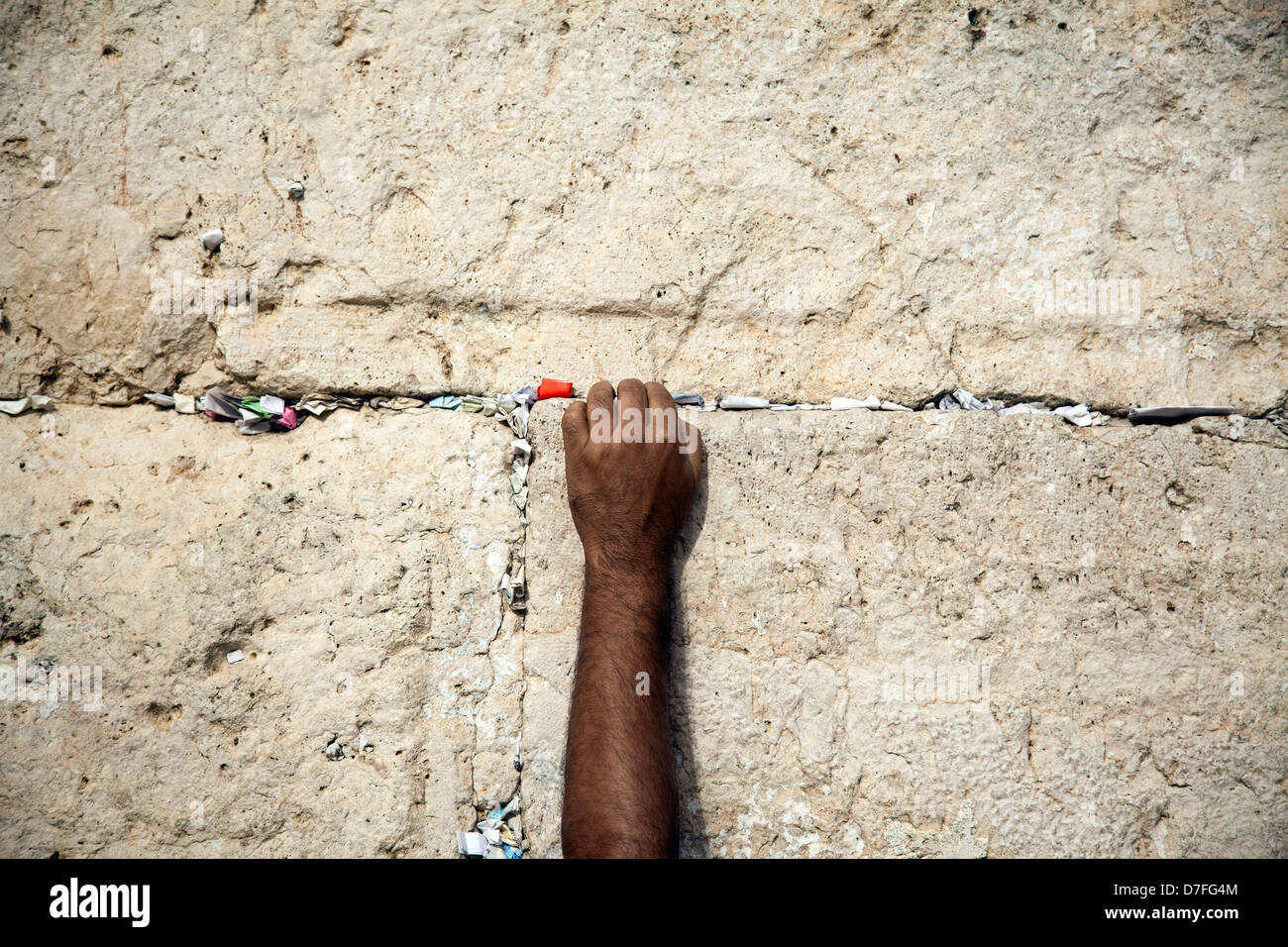 Die linke Hand eines erwachsenen männlichen Platzierung HinweisIn Risse heilige Klagemauer in der Altstadt Jerusalem Israel. Platzieren von Notizen mit Stockfoto