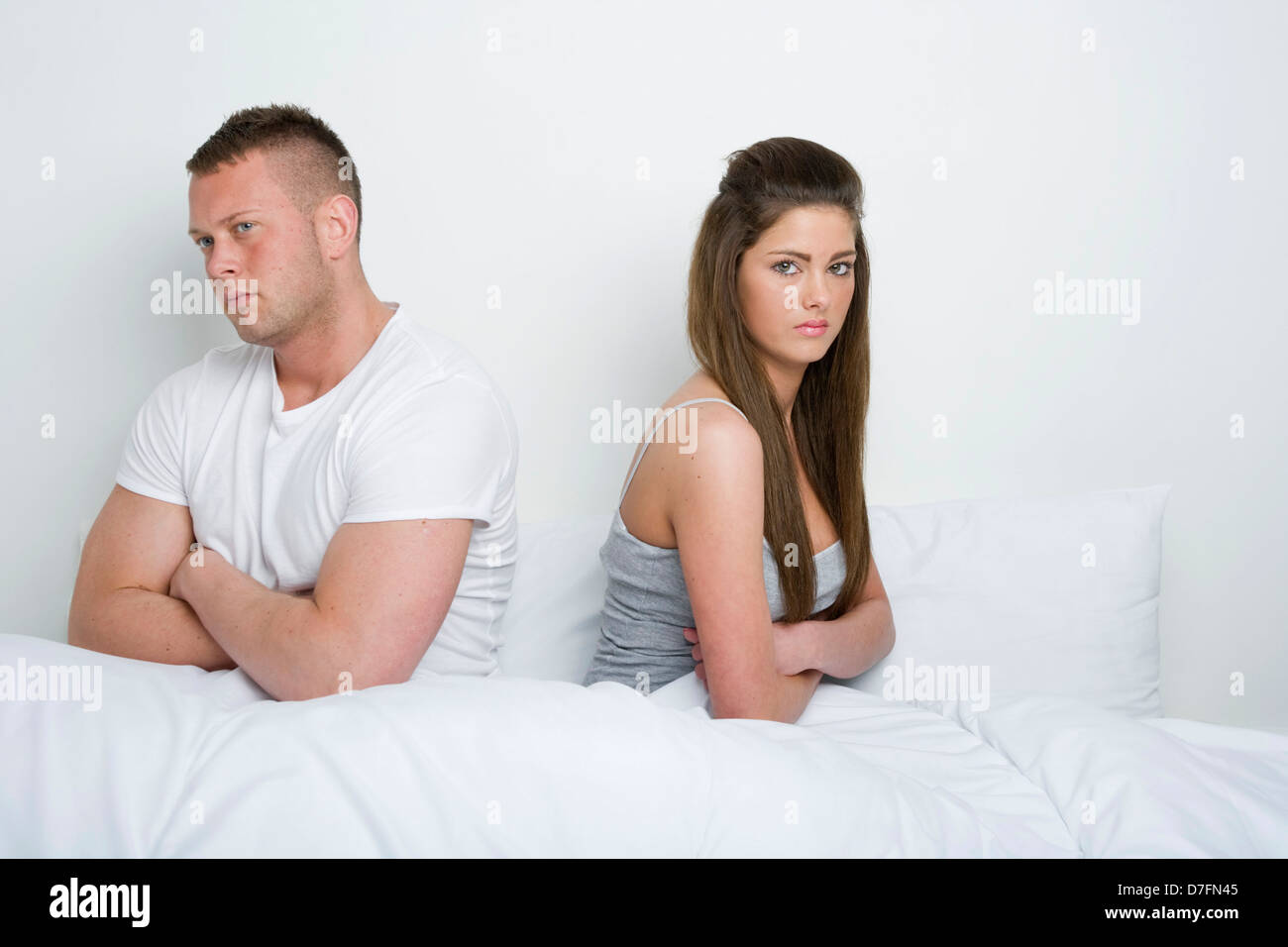 Unglückliche junge Paar sitzen Rücken an Rücken im Bett. Stockfoto