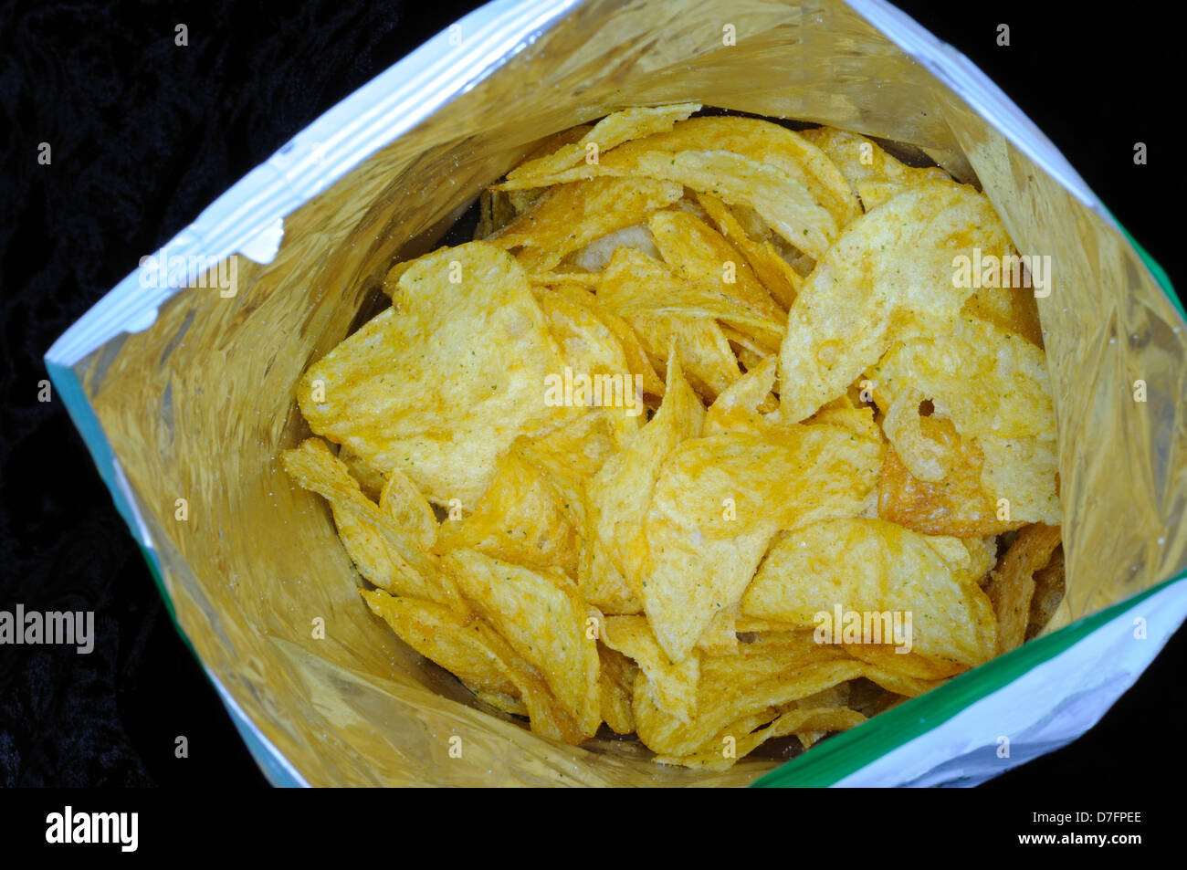 Tomaten und Knoblauch gewürzt Chips in einem Paket vor einem schwarzen Hintergrund. Stockfoto