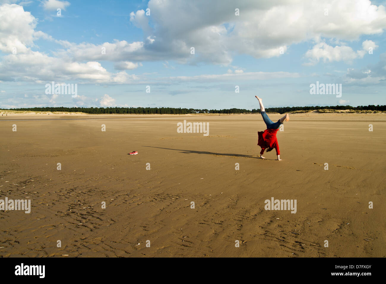 Frau tut eine Warenkorb-Rad am Holkham Beach in Norfolk Stockfoto