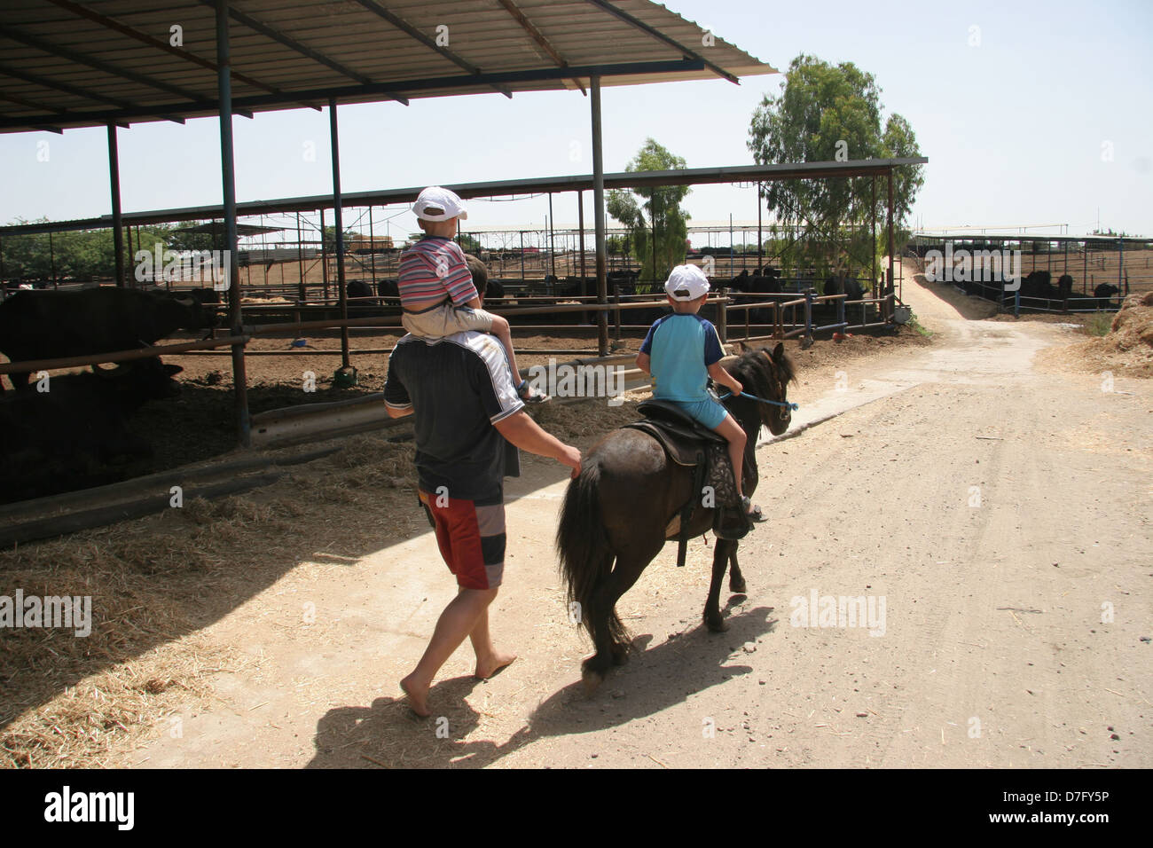 Vater sein Kind, das Ponyreiten in Bitzaron Begleitung Stockfoto