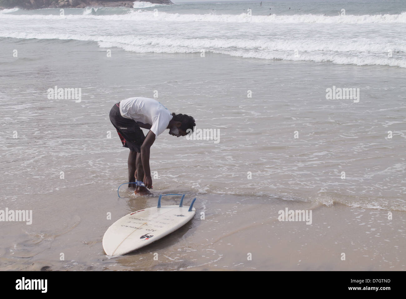Ein Surfer binden seine Surf-Board an seinem Bein vor dem Sprung ins Meer Stockfoto