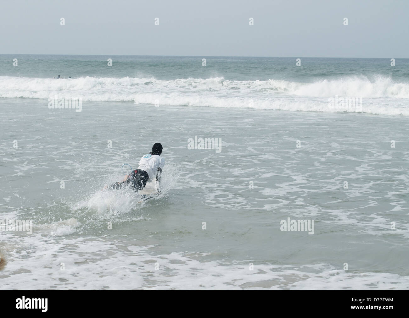 Ein junger Surfer Tauchen in das Meer mit seinem Surf-Brett Stockfoto