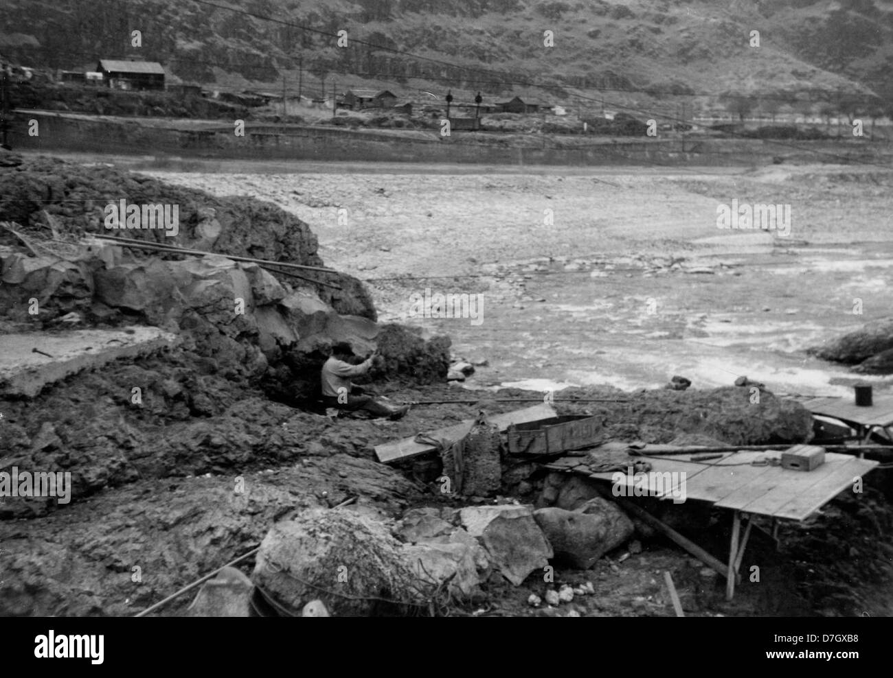 Dieses historische Foto zeigt einen Mann beim Angeln an den Celilo Falls am Columbia River, einem Ort von kultureller Bedeutung für indianische Gemeinden. An diesem legendären Ort werden traditionelle Fischerpraktiken gezeigt. Stockfoto