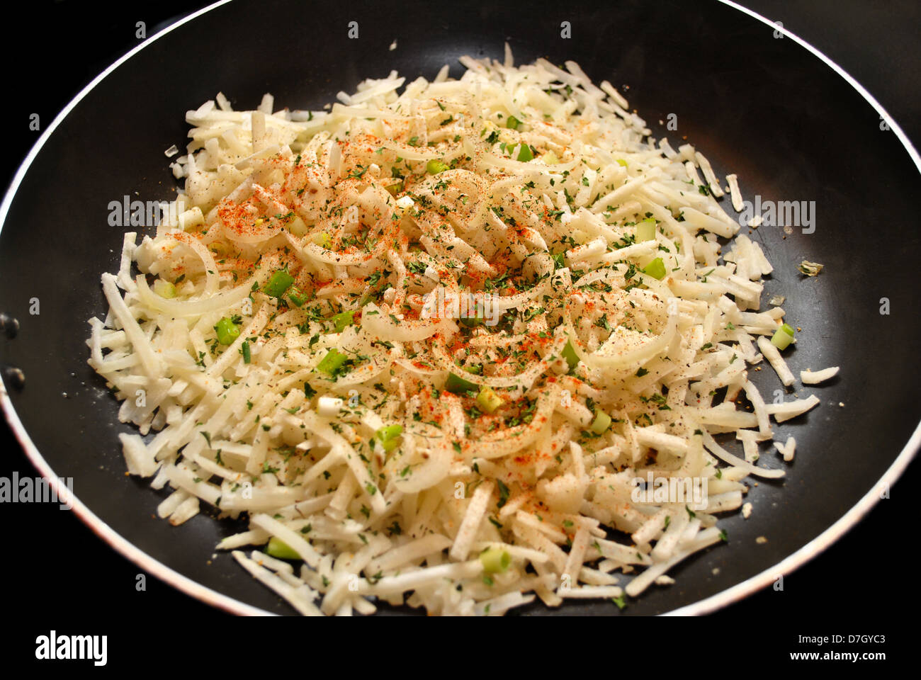 Rohe Hasbrown Kartoffeln mit Gewürzen in einer Pfanne anbraten Stockfoto