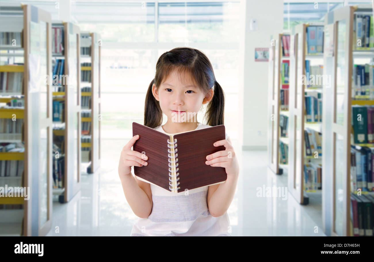 Smart aussehende kleine chinesische Schulmädchen lesen in der Bibliothek Stockfoto