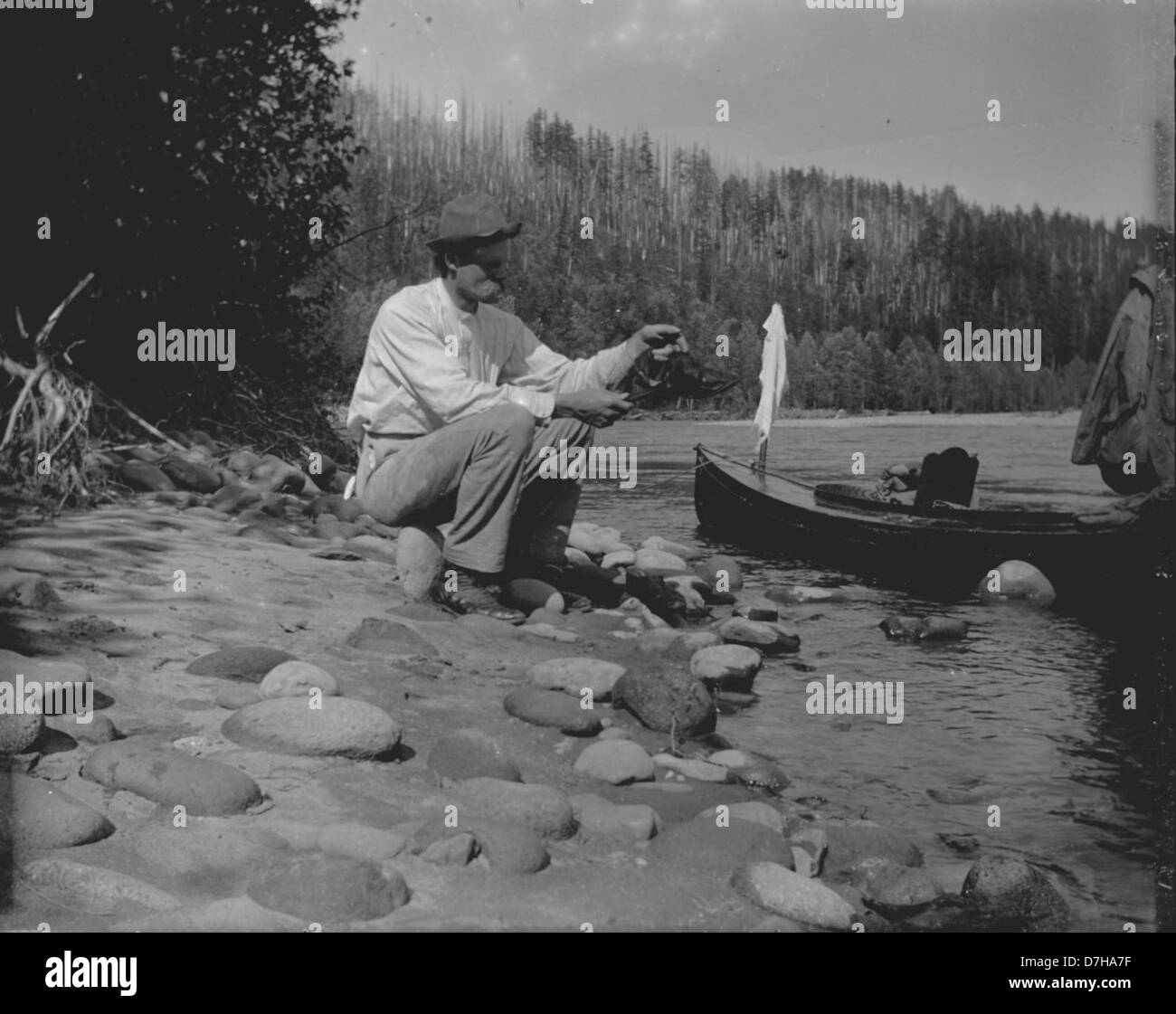 Herman Bohlman, ein amerikanischer Fotograf, sitzt an einem Flussufer, in einem ungeposierten Außenfoto aus dem 20. Jahrhundert, Teil der Herman-Bohlman-Sammlung in den OSU-Archiven. Stockfoto
