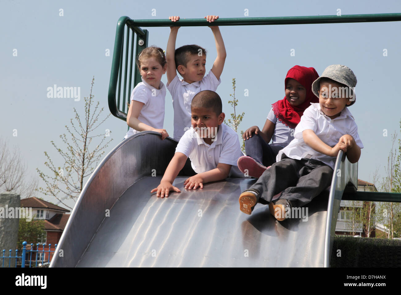 Kinder spielen auf einer Folie auf einem Spielplatz in London Stockfoto