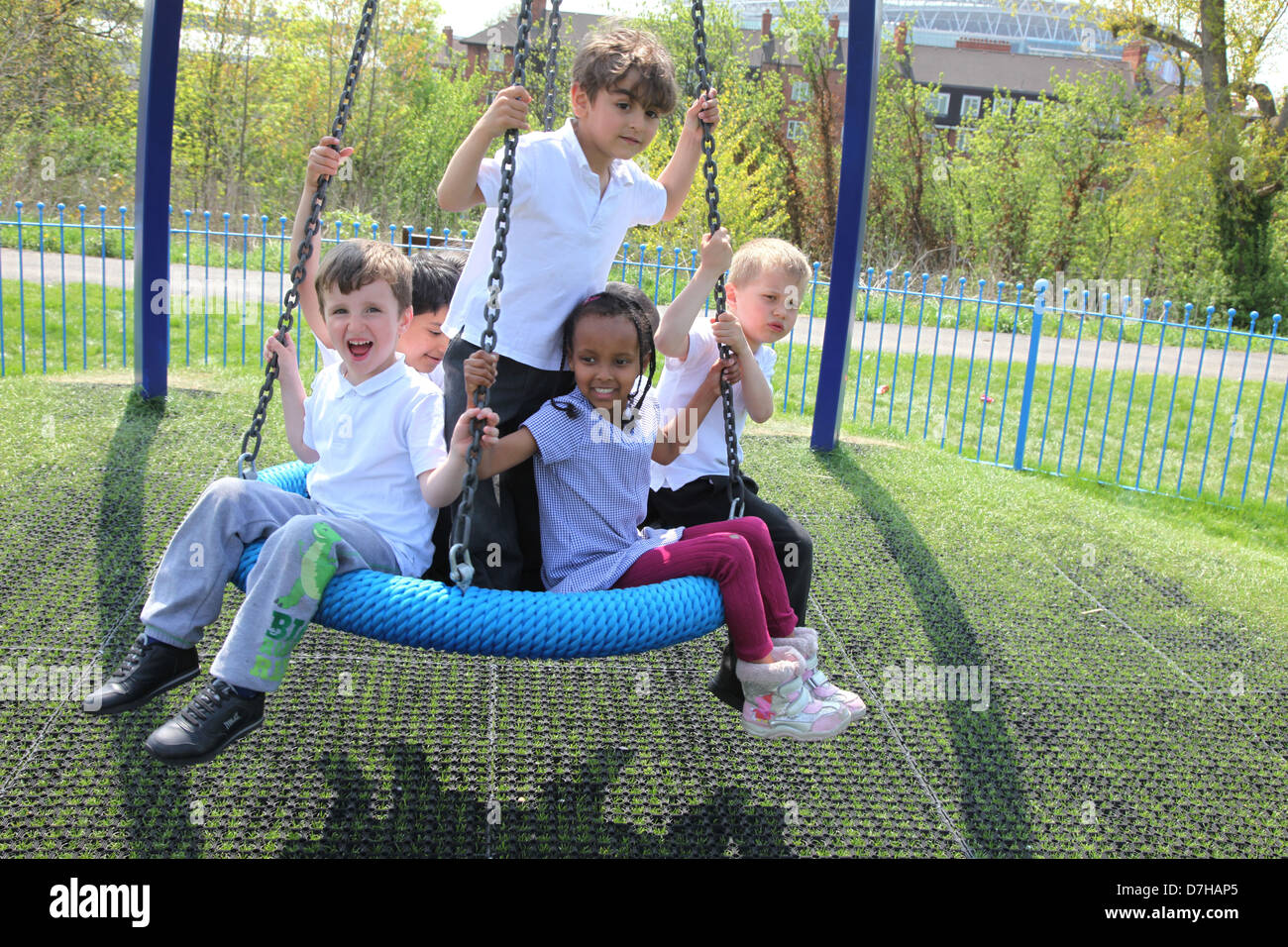Kinder spielen auf einem Reifen / Reifen-Schaukel auf einem Spielplatz in London. Stockfoto