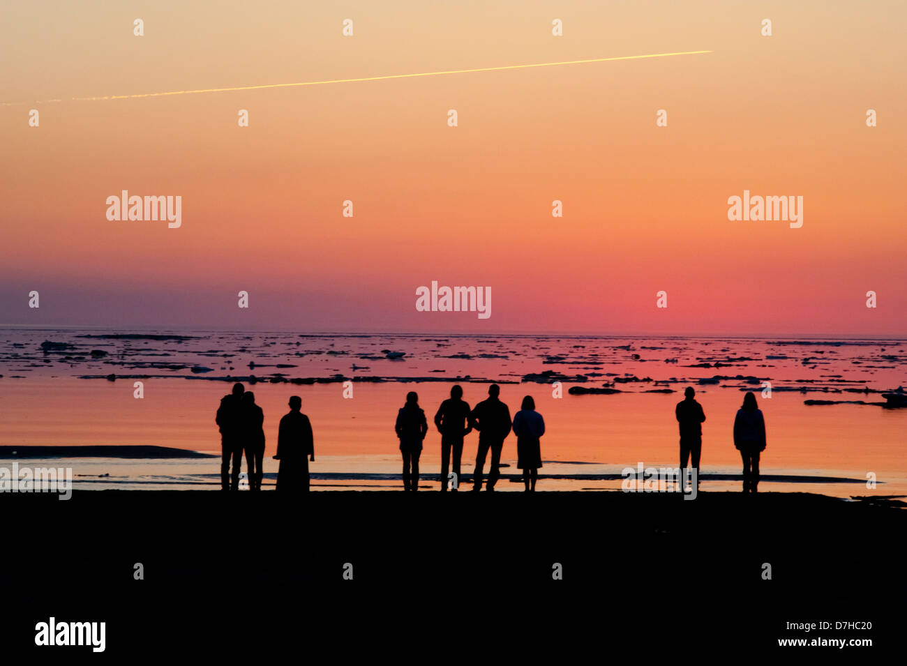 Menschen beobachten Sie den Sonnenuntergang über der Bucht von Riga, Eisberge und ein Flugzeug frei nehmen. Stockfoto