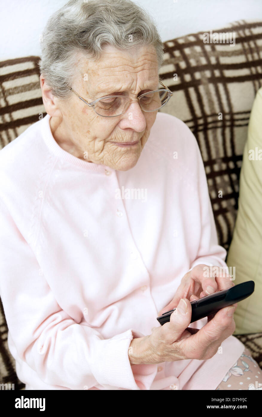 Ältere Frau mit einem spezialisierten großen Knopf Telefon telefonieren die 111 nicht Notfall medizinische Beratung Hotline wegen Krankheitsgefühl Stockfoto
