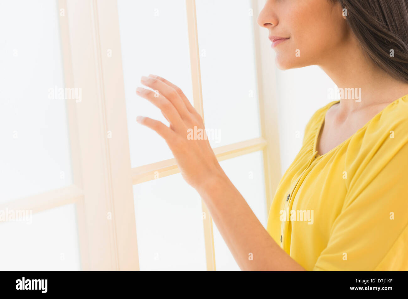 Frau, die durch Fenster Stockfoto