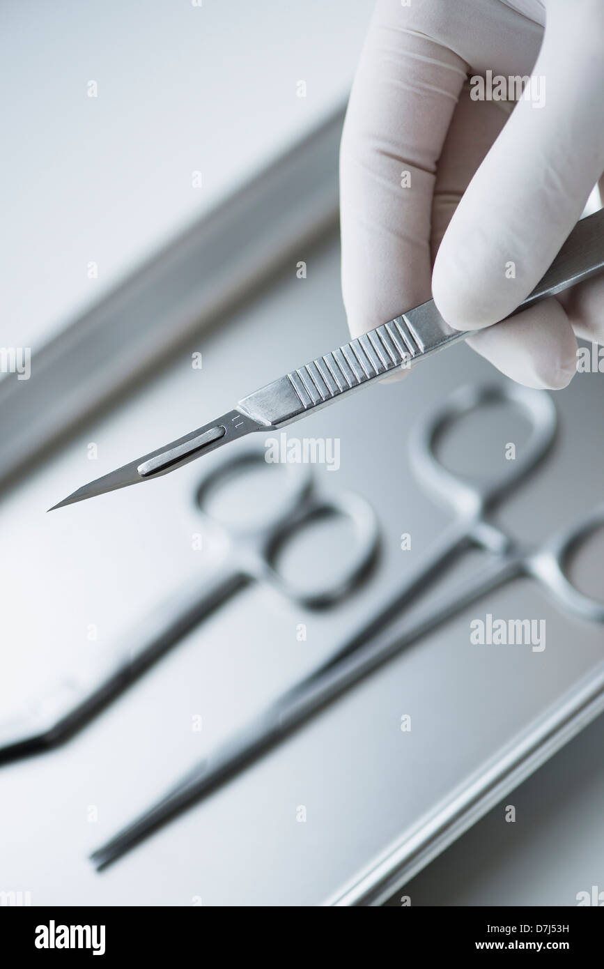 Nahaufnahme von Hand in OP-Handschuh hält dental Skalpell, Studio gedreht Stockfoto