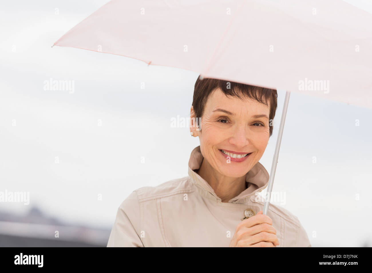 Porträt von lächelnden Frau mit Regenmantel und Holding-Dach Stockfoto