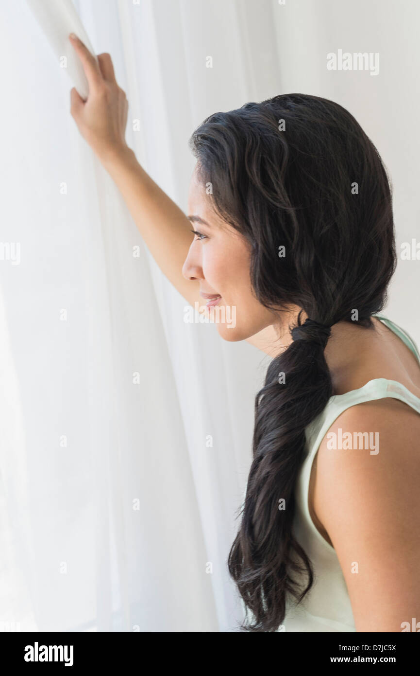 Junge Frau, die durch Fenster Stockfoto