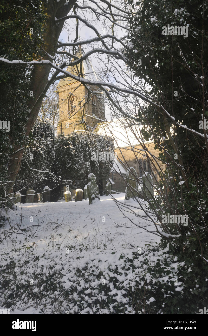 Kirche im Sonnenlicht, Friedhof, Grabsteine, Schnee, Bäume, Büsche, blauer Himmel, Wald Stockfoto