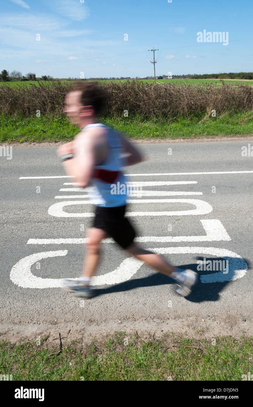 Ein Mann läuft vorbei an einem langsamen Schild mit Motion blur Stockfoto