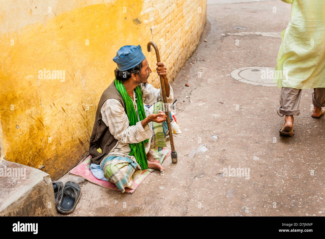 Bettler sucht Almosen auf einer schmalen Straße in Nizamuddin, einem muslimischen Vorort von Alt-Delhi, Indien. Stockfoto