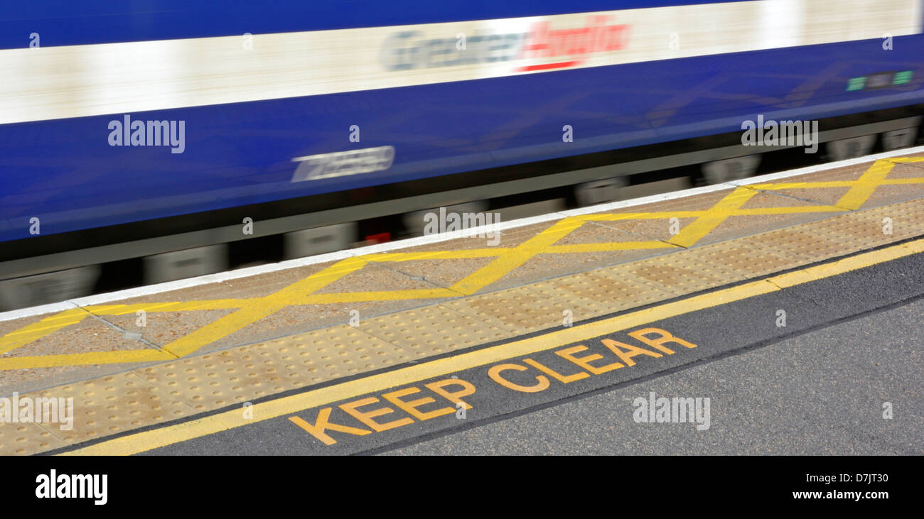 Freihalten Sie, Warnzeichen nicht Pflasterung und gelbe Linie schlüpfen entlang Bahnhof Bahnsteig mit Schnellzug vorbei rutschen Stockfoto
