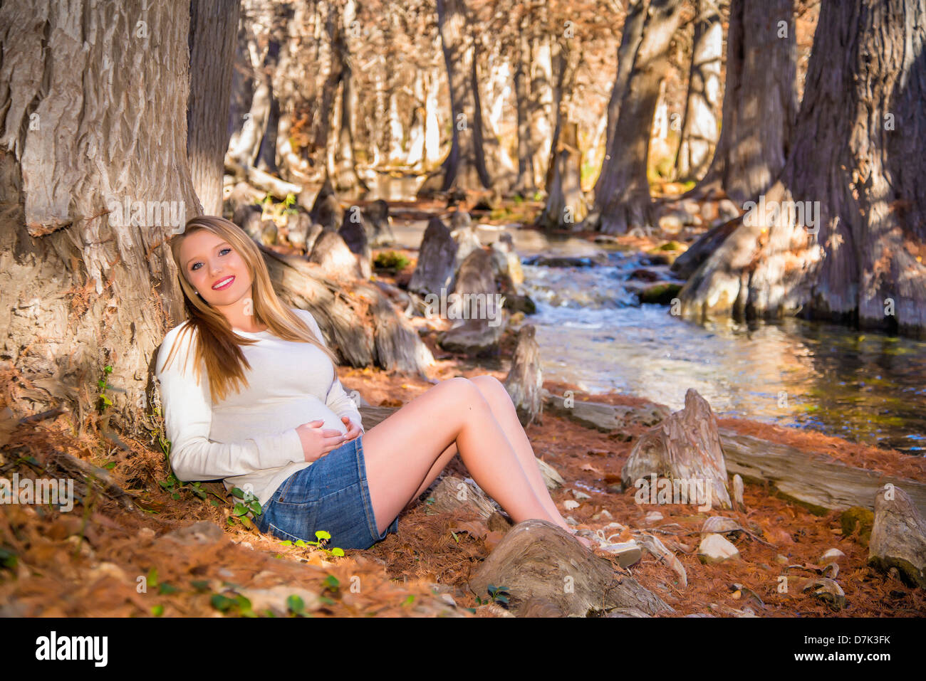 USA, Texas, schwangere junge Frau sitzt auf dem Creek, Lächeln, Porträt Stockfoto