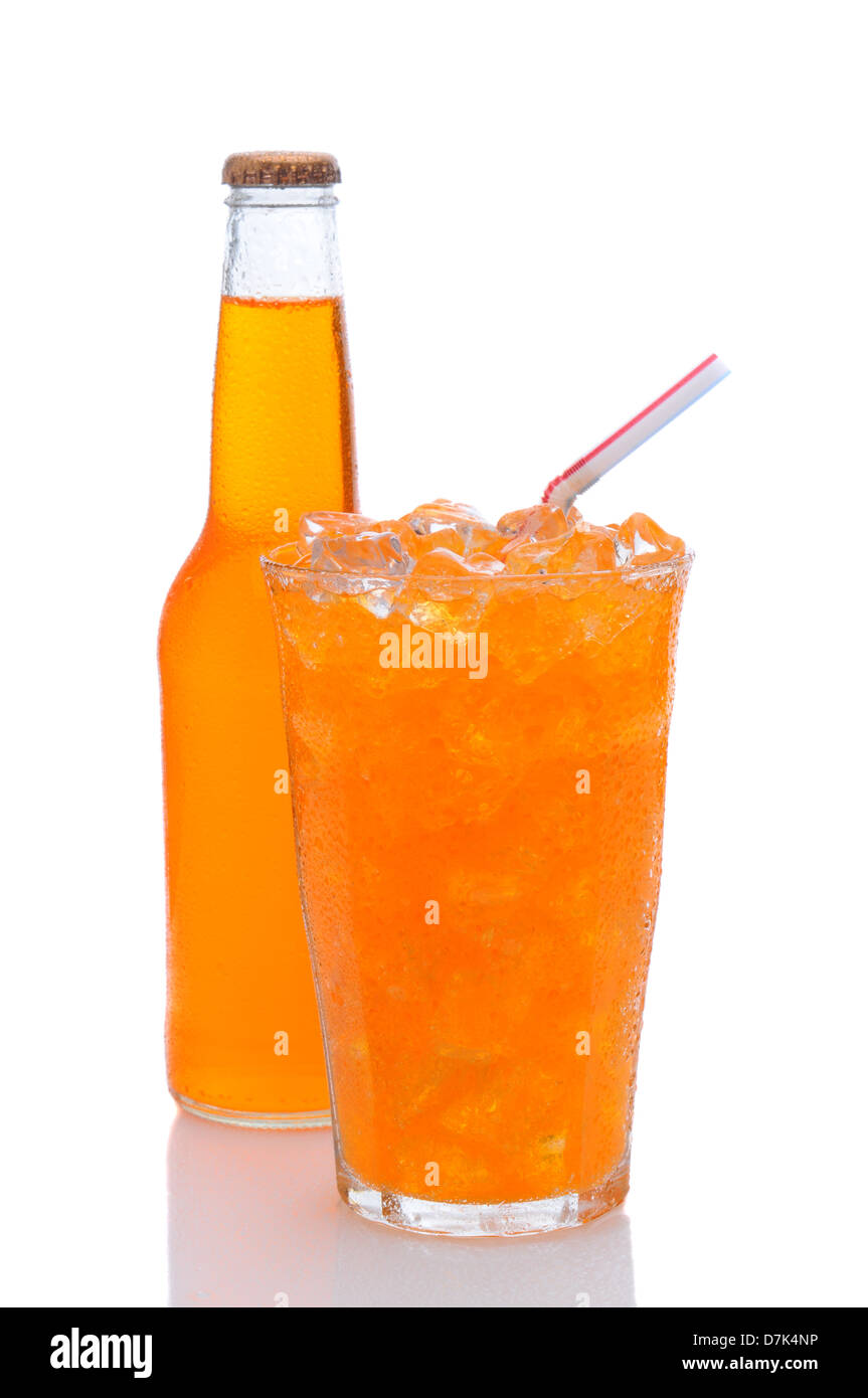 Ein kaltes Glas Orangenlimonade gefüllt mit Eis und einen Trinkhalm mit einer Flasche versteckt hinter. Stockfoto