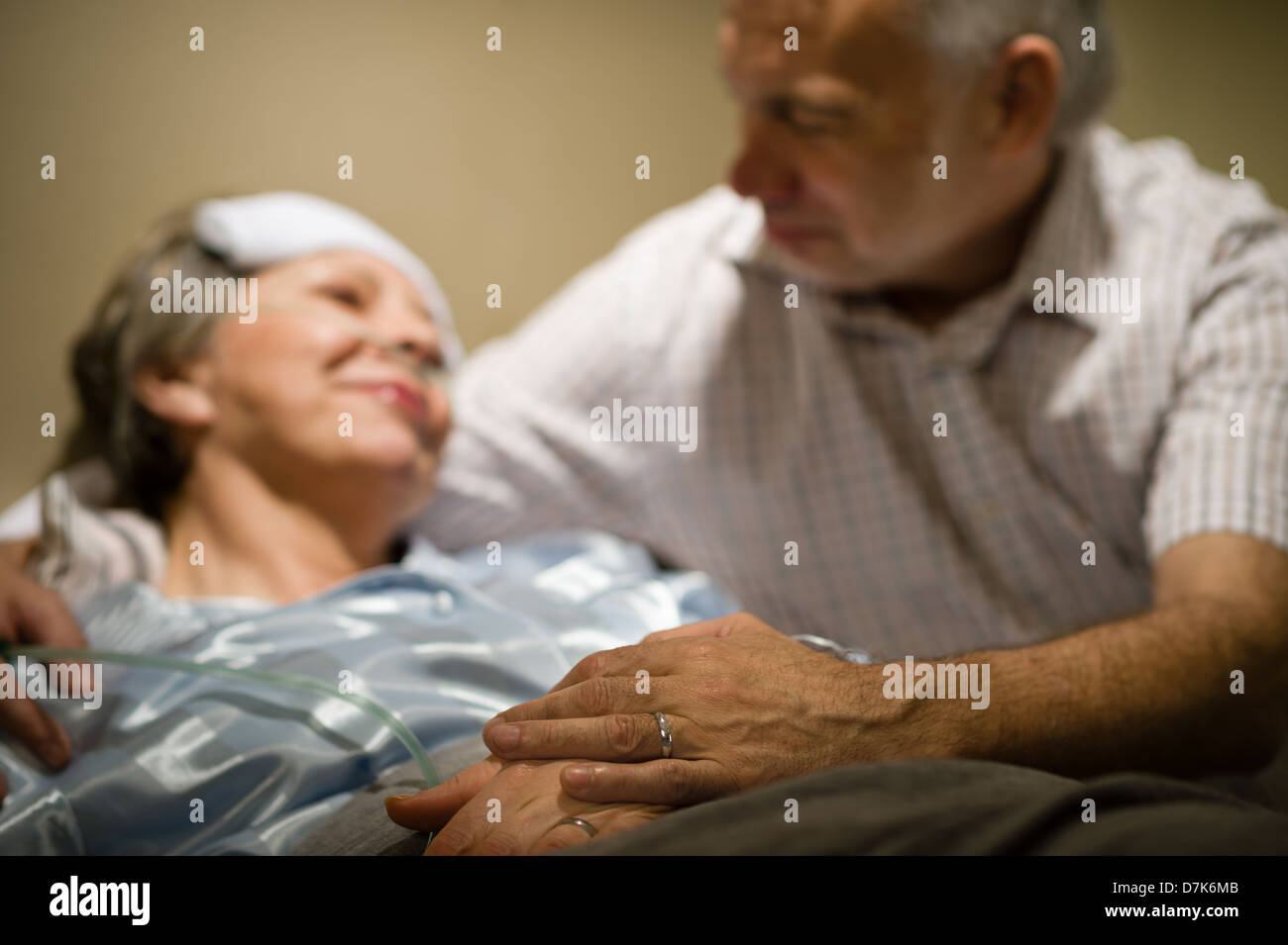 Alte Frau in Schmerzen liegen Bett Hand in Hand mit Ehemann Stockfoto