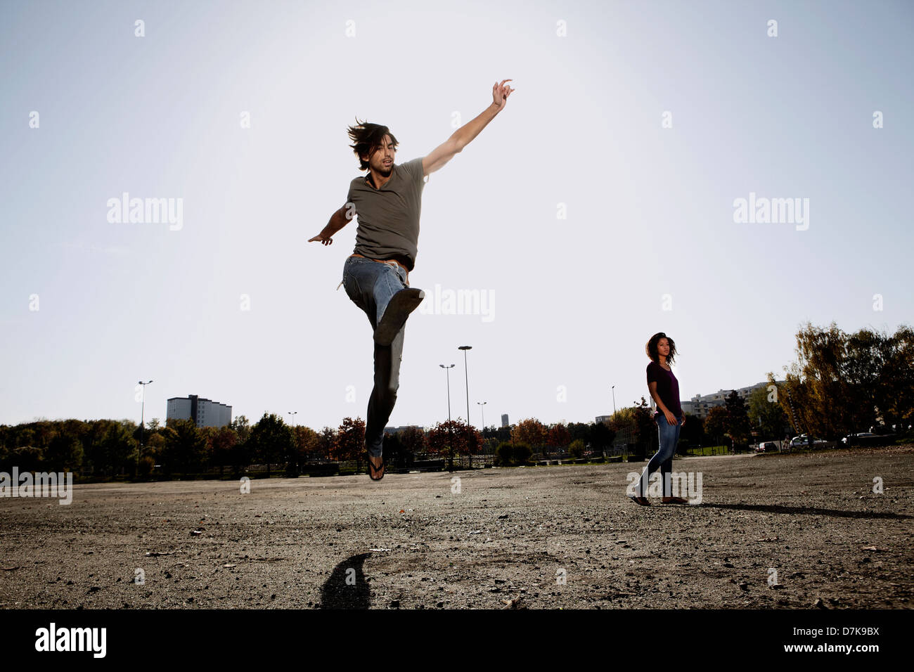 Deutschland, Köln, Mann springt im Feld, Frau im Hintergrund Stockfoto