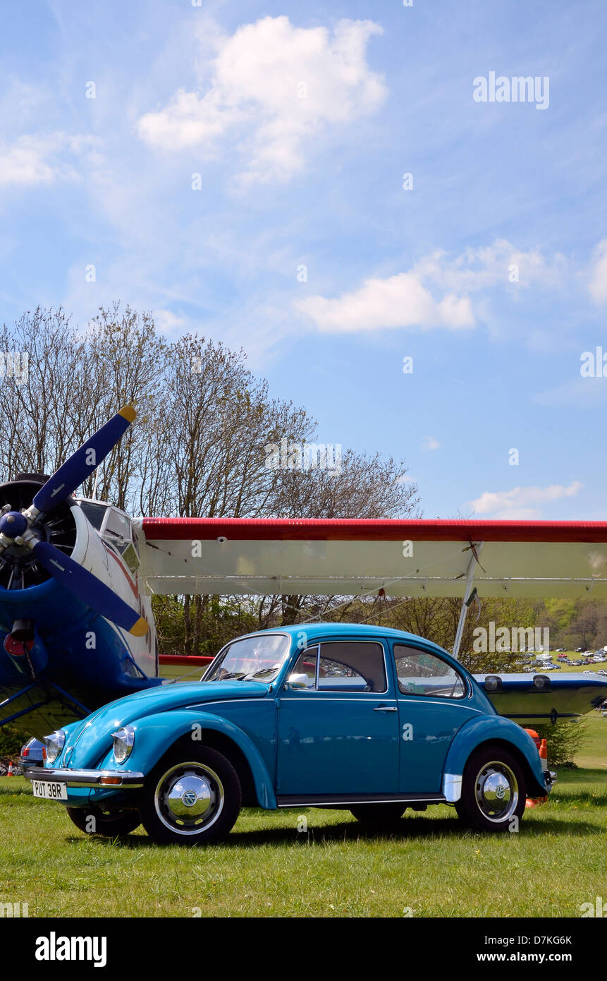 Klassische 1960er VW Käfer vor einer Antonov An-2 Doppeldecker abgebildet. Stockfoto