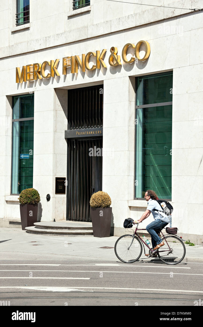 Mann Reiten Fahrrad vorbei an Merck Finck & CO Privatbankiers Bürogebäude, München, Upper Bavaria Germany Stockfoto