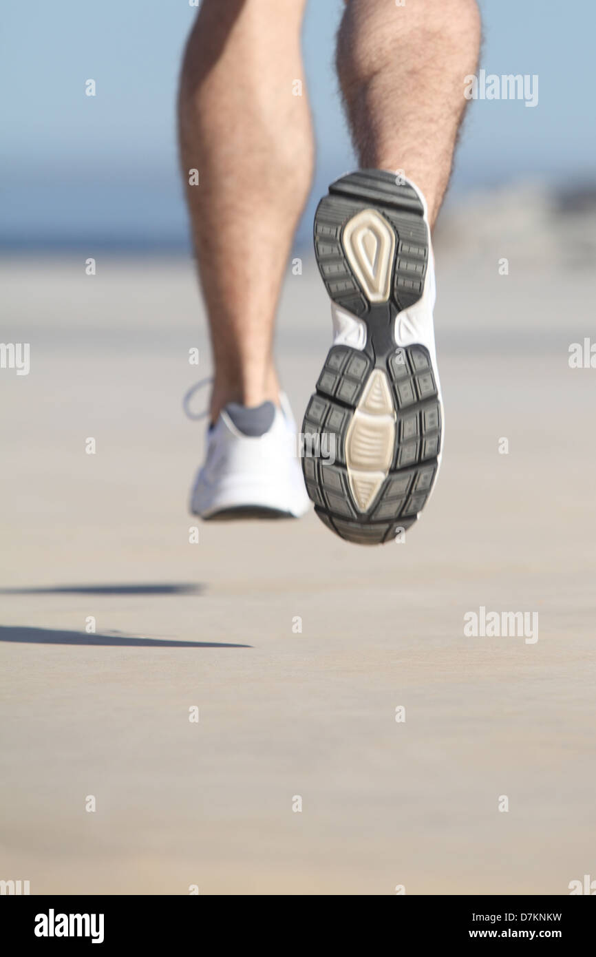 Nahaufnahme einer unkonzentrierten Mann Beine auf dem Beton eine Strandpromenade mit den Himmel im Hintergrund laufen Stockfoto