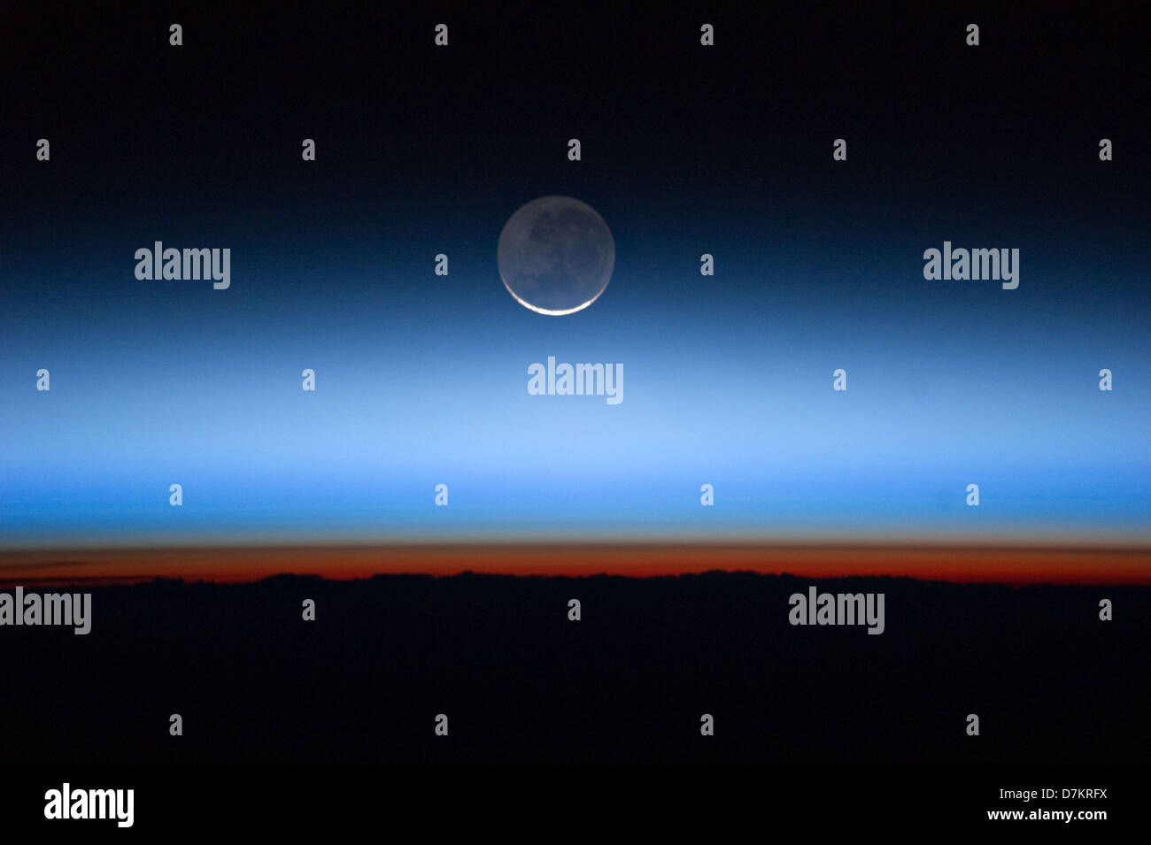 Mond mit den Leib der Erde im unteren Übergang in der orangefarbenen Troposphäre, die unterste und dichteste Teil der Atmosphäre der Erde. Die Troposphäre endet abrupt an der Tropopause, die als die scharfe Grenze zwischen Orange und blau gefärbten Atmosphäre im Bild erscheint. Die silbrig-blauen Nachtwolken erstrecken sich weit über die Erde Troposphäre. Stockfoto