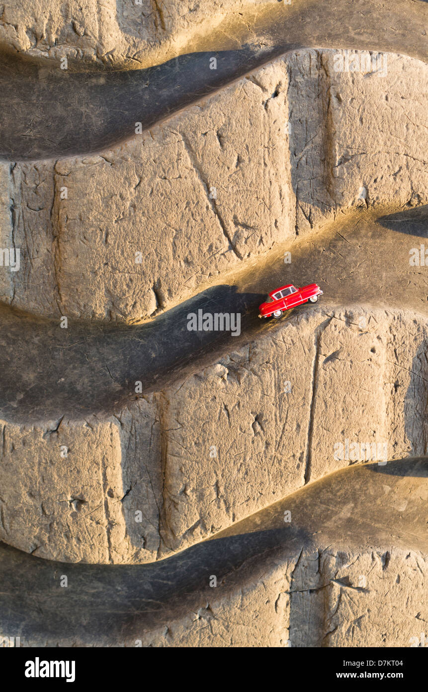 Kleinen roten Spielzeugauto in Spuren der großen LKW-Reifen Stockfoto