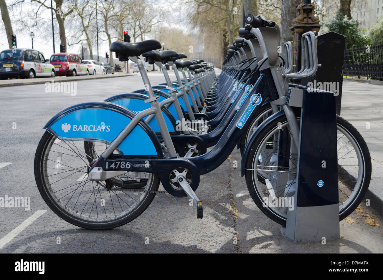 Boris Bikes am Bahndamm London aufgereiht warten darauf, mit schwarzen Taxis Taxis und Verkehr im Hintergrund gemietet werden Stockfoto