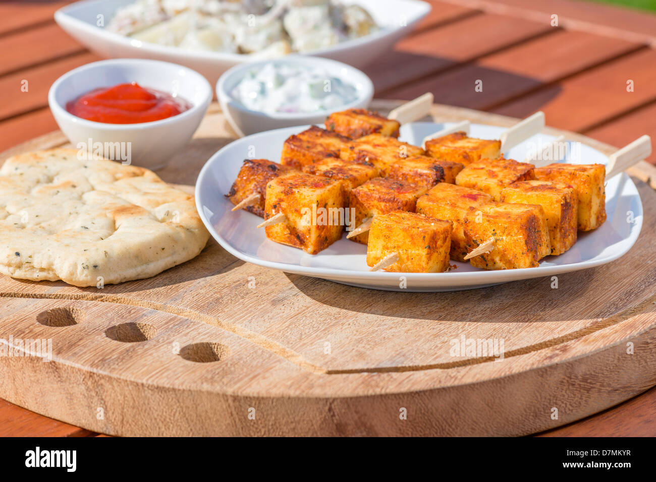 Paneer Tikka Kebab - Tadoori indischer Käse Spieße mit Naan-Brot, Chili-Soße und Gurke und Joghurt Raita. Essen im freien Stockfoto