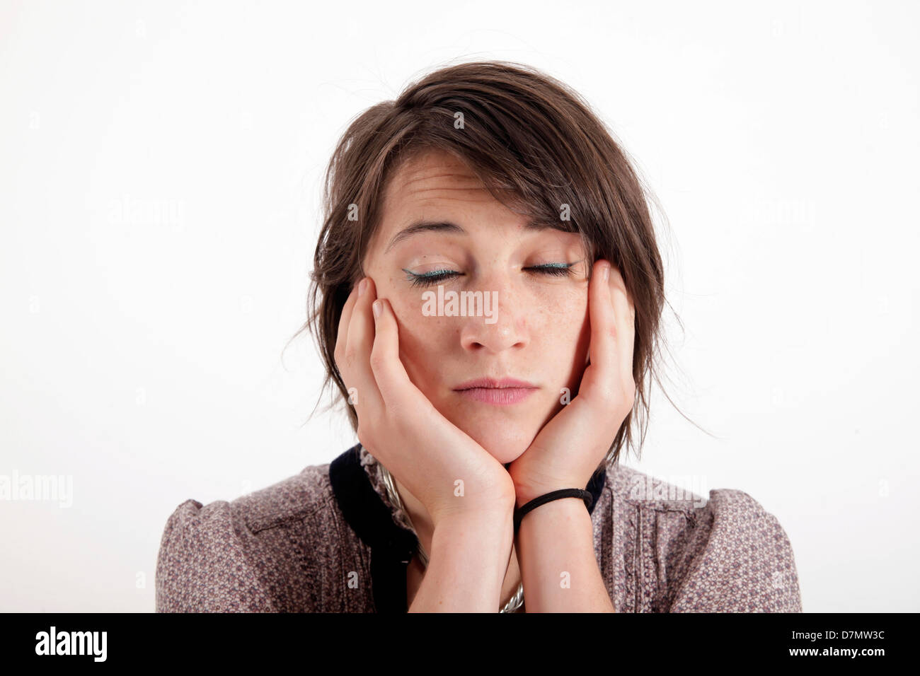 Junge Frau mit der Hand unter ihr Gesicht isoliert im Studio mit Blick Stockfoto