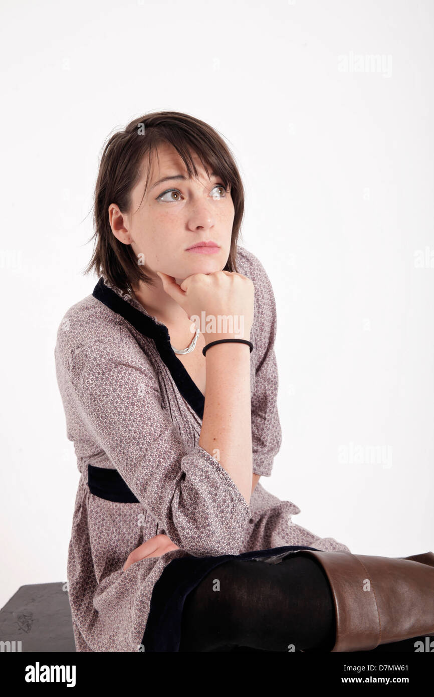 Junge Frau mit der Hand unter ihr Gesicht isoliert im Studio mit Blick Stockfoto