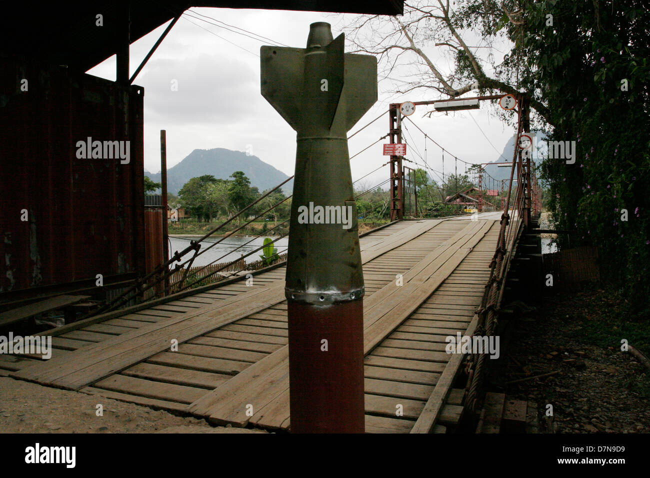 Vang Vieng befahrbare Brücke ist flankiert von Kampfmitteln aus dem Geheimnis-Krieg der USA in den 1960er und 1970er Jahren in Laos orchestriert. Stockfoto